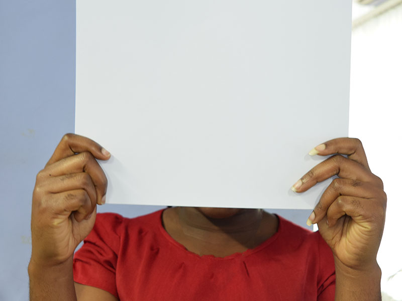 Black girl holding blank sheet of paper in front of her face