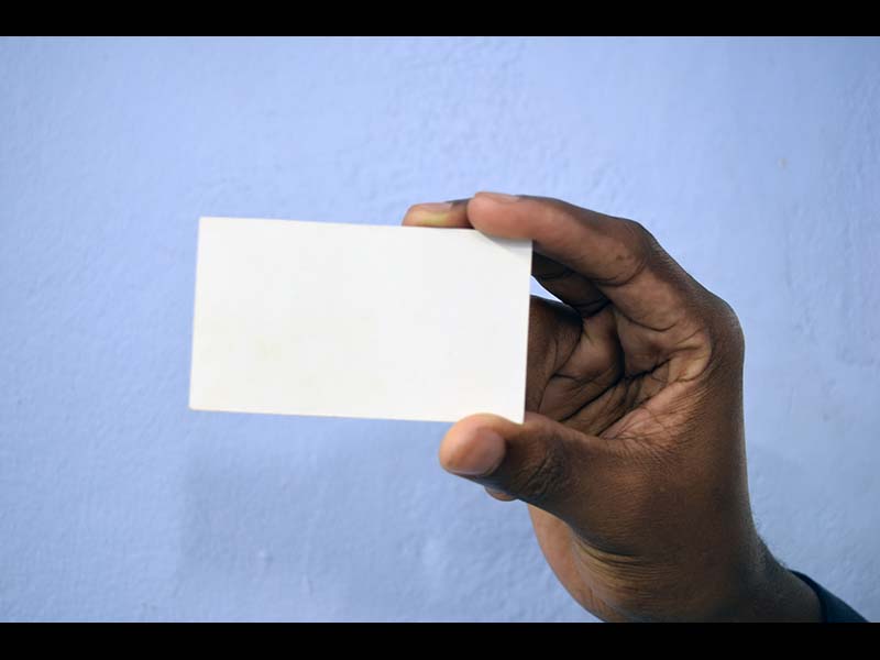 Black African hand holding blank business card on blue background