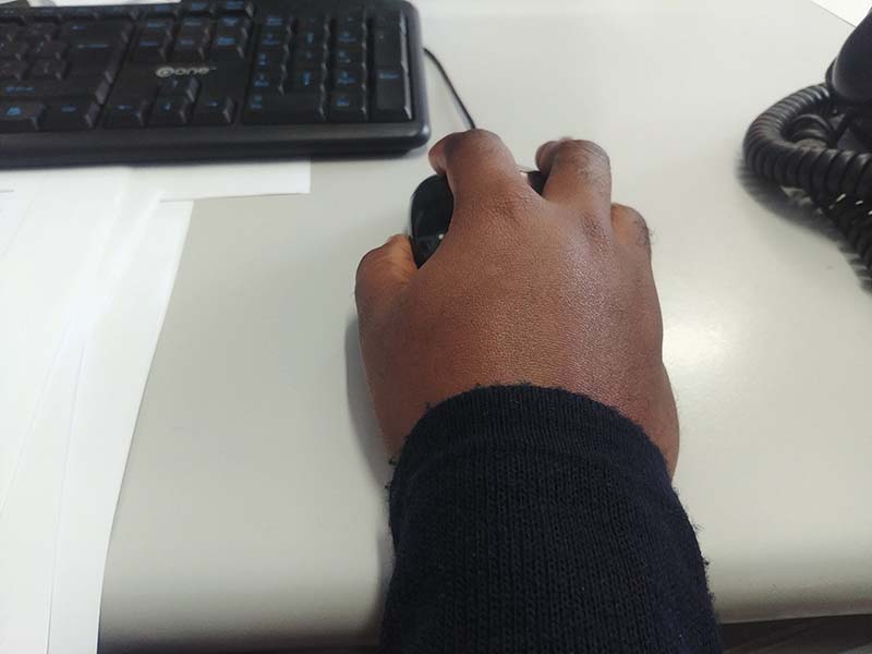 Black hands using mouse at a desk