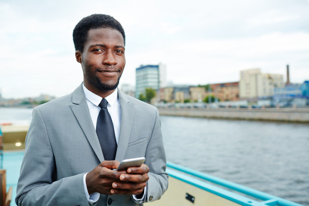 Young African black business man manager using mobile phone on upper deck of ship – Free Photo