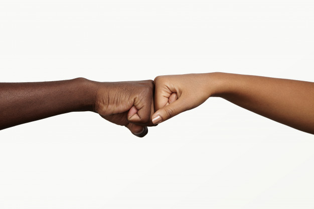 African man touching knuckles with dark-skinned woman as sign of agreement, partnership and cooperation. Free Photo