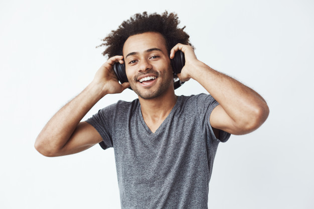 Happy African American black man smiling listening to music in headphones - ear buds - Free Photo