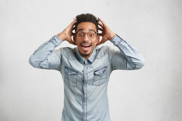 I can`t believe in this! amazed African American black man holds hands in surprised gesture, keeps mouth wide opened and bugged eyes Free Photo