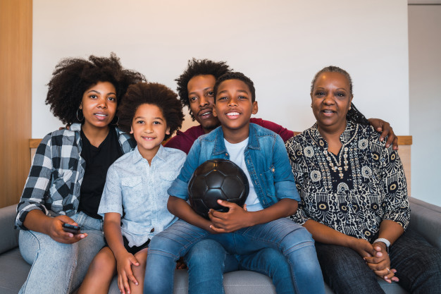 Multi-generation family watching soccer match at home. Free Photo