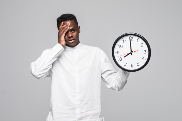 Portrait of a afro american man holding wall sleepy clock 7 o'clock in the morning isolated on a white background Free Photo