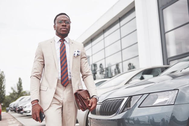 Visiting car dealership. casual black business man in a suit near the car. Free Photo