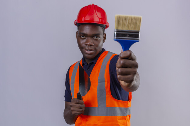 Young african american builder man wearing construction vest and safety helmet showing paint brush stretching out looking confident on isolated white Free Photo