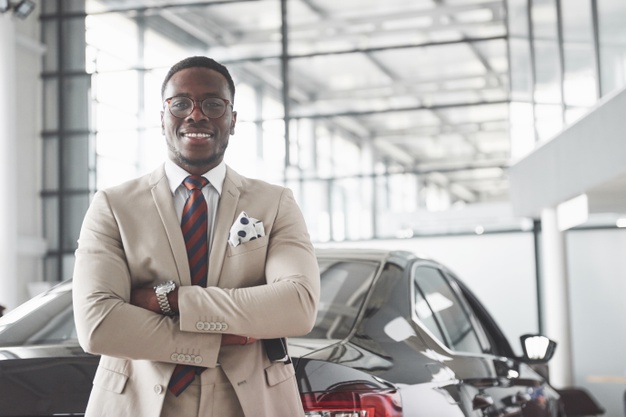 Young black businessman on auto salon. car sale and rent concept. Free Photo