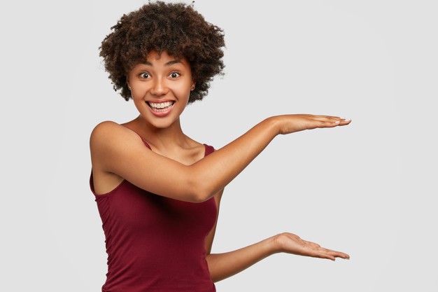 African American black young woman with pleased facial expression shows height of something Free Photo