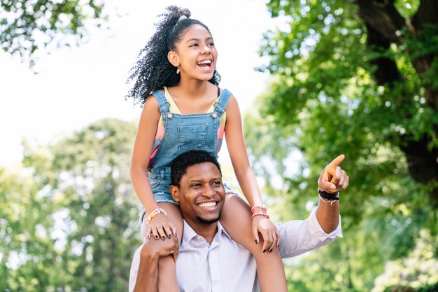 African black father and his daughter having fun and spending time together while walking outdoors on the street