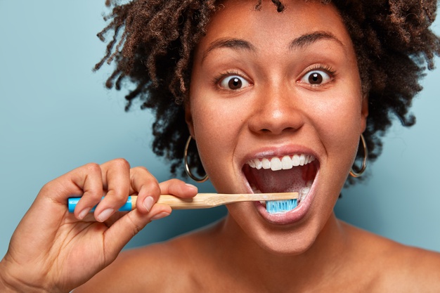 Glad Mirthful Woman With Dark Healthy Skin Satisfied With New Toothpaste Cleans Teeth Opens Mouth Widely Has Happy Expression Curly Hair Models Blue Wall Close Up Portrait 273609 26524