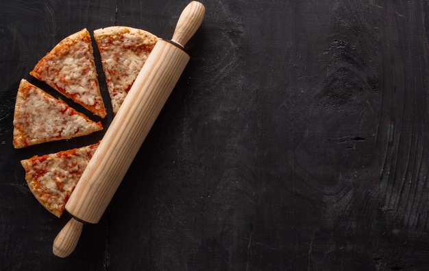 High angle shot of pizza pieces and a wooden roller on a wooden Free Photo