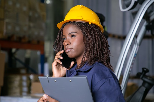 African black woman engineer in hardhat and talking on phone