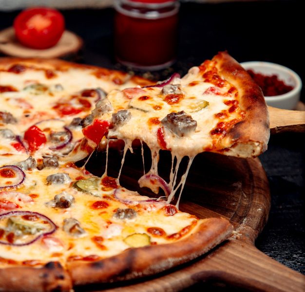 A slice of crispy pizza with meat and cheese Free Photo