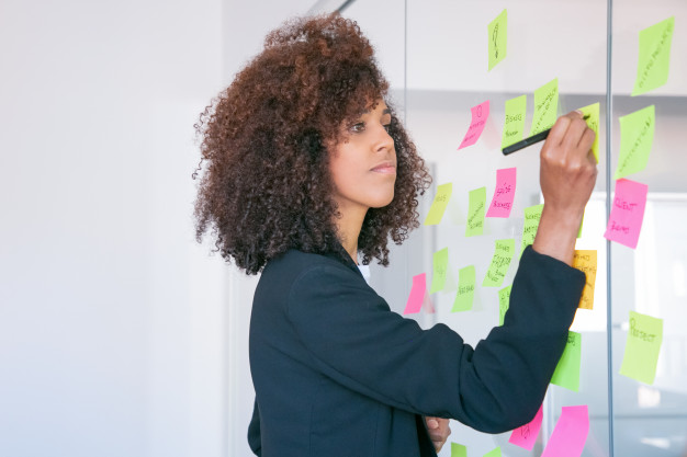 African black businesswoman writing on sticker with marker