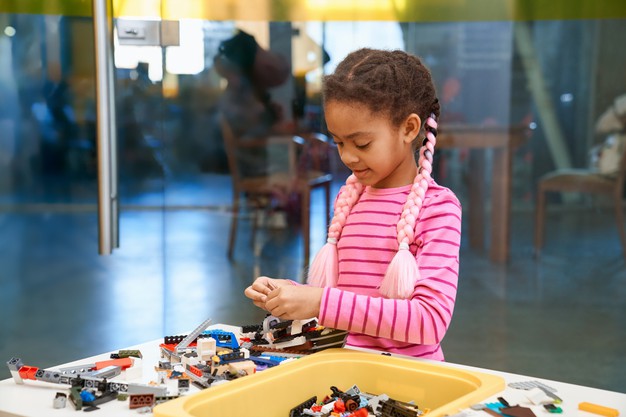 African black little girl playing with building kit or Legos