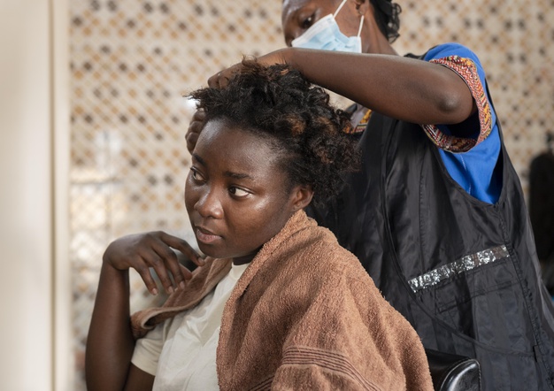 African black woman getting her hair done at the beauty salon Free Photo