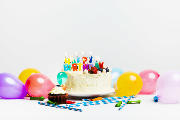 Tasty cake with berries and happy birthday title near colourful balloons Free Photo
