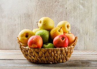 Apples with drops in a wicker basket on light wooden and grunge Free Photo