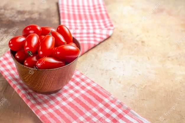 Front view cherry tomatoes in wooden bowl a kitchen towel on amber free space Free Photo