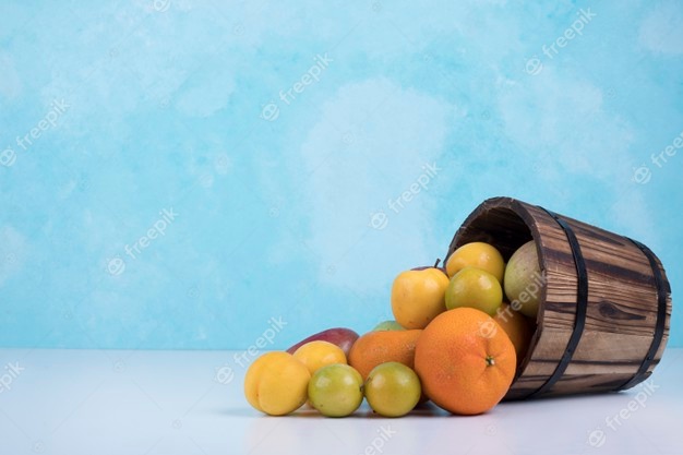 Summer fruits mix out of a wooden bucket on blue. Free Photo