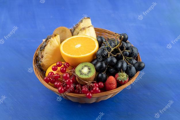 A wicker basket full of fruits on blue surface Free Photo