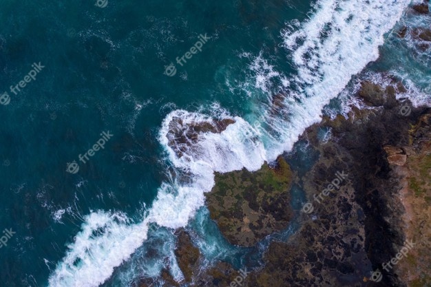 Aerial view of waves crashing on rocks Free Photo