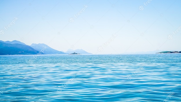 Beautiful shot of sea with a mountain in the distance and a clear sky Free Photo