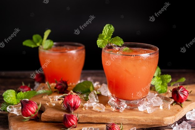 Iced roselle tea glass with fresh roselle fruit on wooden table for healthy herbal drink concept. herbal organic tea for good healthy. Free Photo