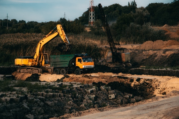 Closeup shot of an ongoing construction with tracks and a bulldozer on an abandoned land Free Photo