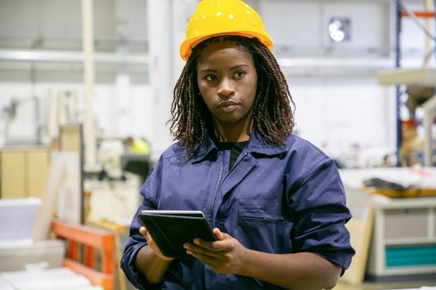 Content female plant worker standing with tablet and looking away Free Photo