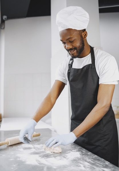 African american baker preparing raw dough for pastry on baking manufacture.kneading dough for pastry Free Photo