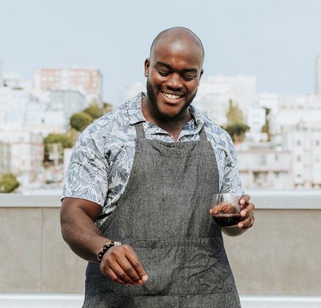 Chef seasoning barbeque skewers at a rooftop party Free Photo