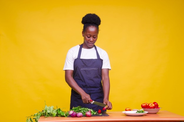 Horizontal shot of a young attractive african cook cutting vegetables with a knife Free Photo