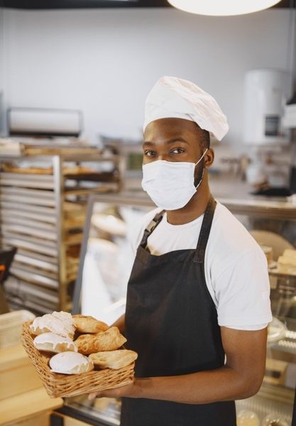 Portrait of african-american baker with fresh bread at the bakery. pastry chef holding small pastry. Free Photo