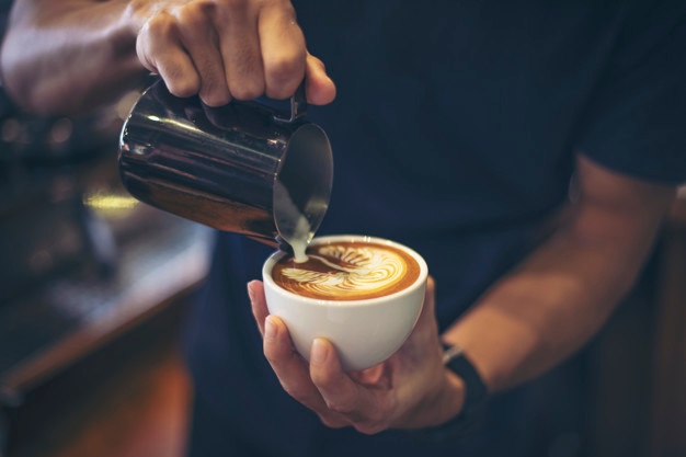 Close-up of hands barista make latte coffee art paint Free Photo