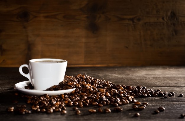 Cup of coffee with a pile of coffee beans Free Photo