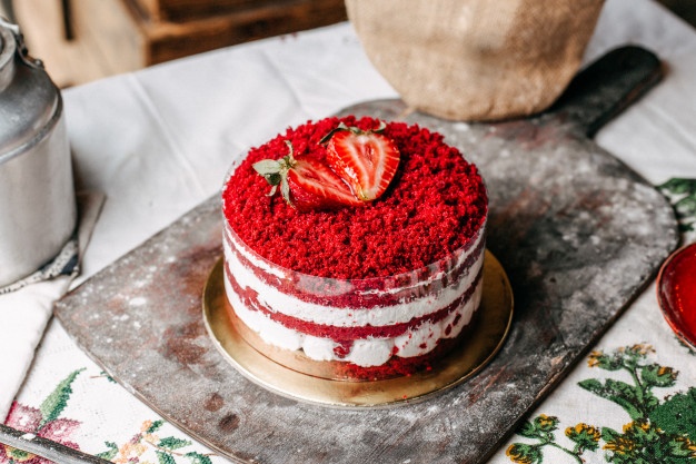 A front view red fruit cake decorated with strawberries round with cream delicious sweet birthday celebration on the brown desk Free Photo