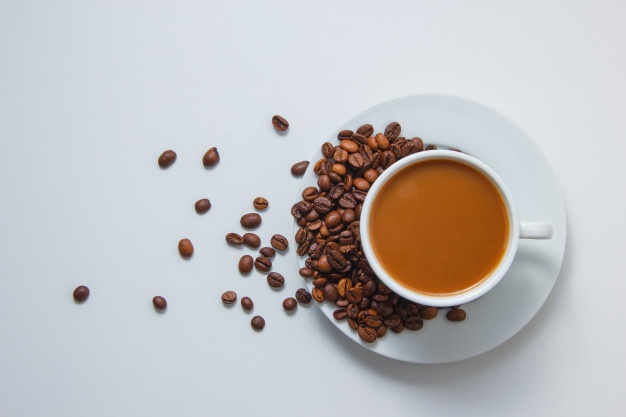 Top view a cup of coffee with coffee beans on saucer on white background Free Photo