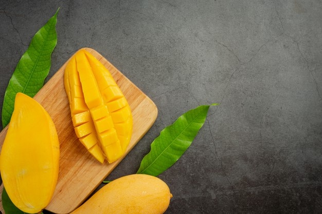 Beautiful chopped ripe mango on dark wooden surface Free Photo