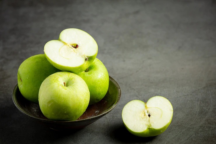 Fresh green apples cut in half put in black bowl on dark background Free Photo