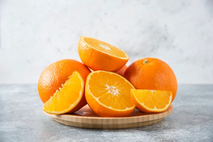 A wooden board full of juicy slices of orange fruit on stone table . Free Photo