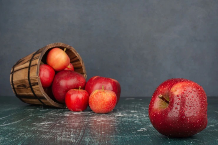 Red apples falling out of bucket on marble table. Free Photo