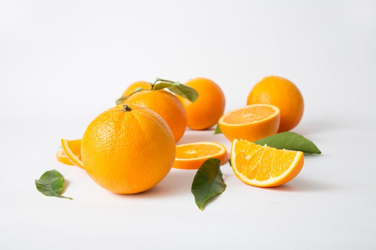 Bright whole oranges with green leaves and cut fruits Free Photo