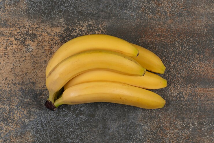 Cluster of ripe bananas on marble surface Free Photo