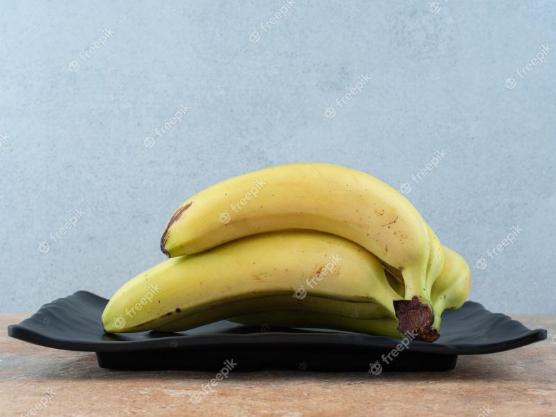 A dark plate full of ripe fruit bananas on gray Free Photo A dark plate full of ripe fruit bananas on gray Free Photo