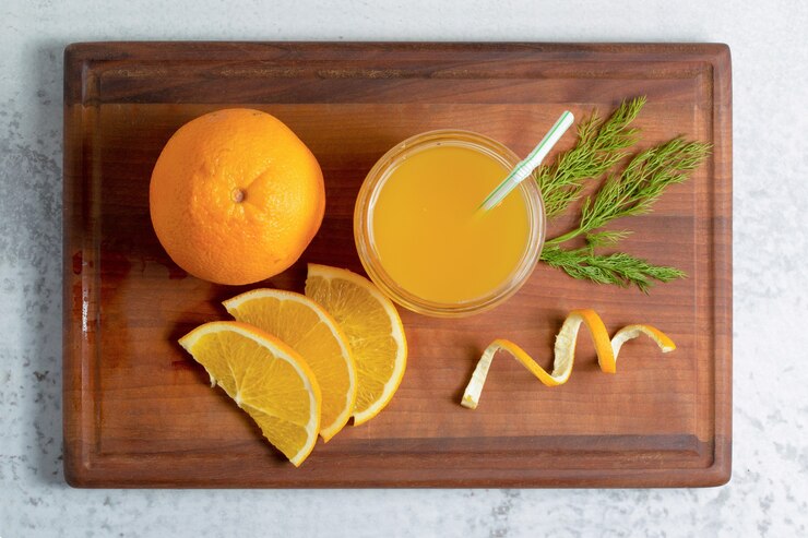 Fresh orange juice with sliced or whole fruits on wooden board. Free Photo