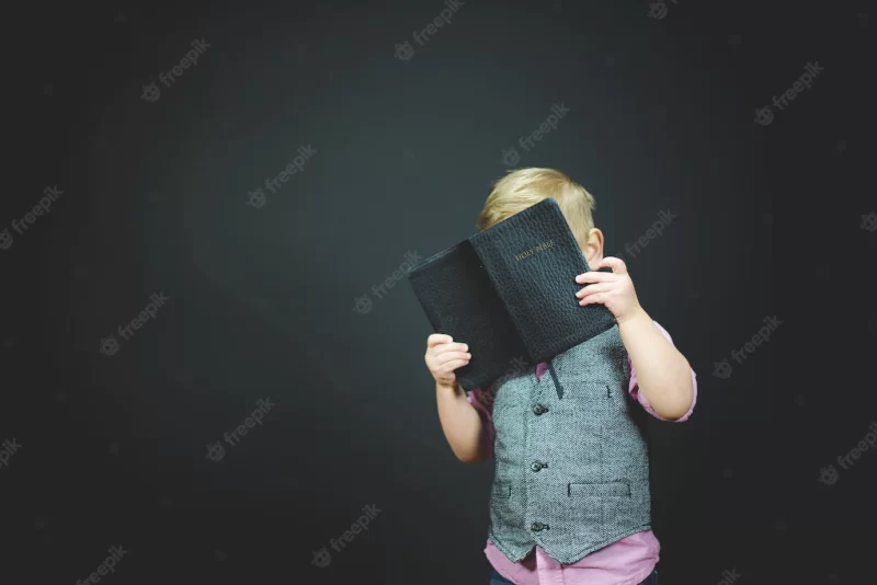 Beautiful shot of a child holding an open bible Free Photo