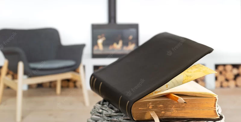 Bible book with pencil, on the background of the living room with a fireplace. reading a book in a cozy