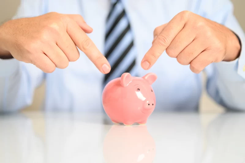 Closeup of a businessman pointing to a piggy bank Free Photo